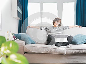 Smiling girl sit relax on couch using modern laptop.happy young woman freelance work on computer from home. social