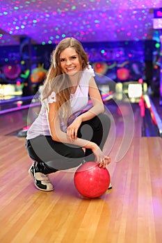 Smiling girl sits with ball in bowling club