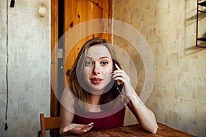 A smiling girl sits at the chair with a phone in her hands waiting for a call