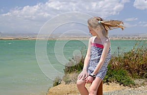 Smiling girl sits on a coast