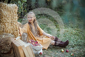 Smiling girl sits near fresh apples that have just been collected in bags