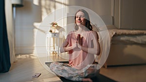 Smiling girl sitting lotus asana in morning sunlight. Carefree woman meditating