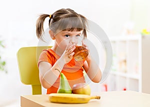 Smiling girl sitting on the table with fruits and