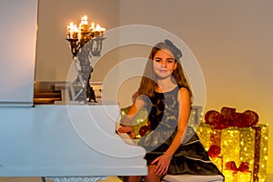 Portrait of Beautiful Smiling Girl Sitting at Piano Looking at Camera.