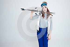 Smiling girl skier in a hat and mask for skiing. A young woman in clothes for skiing and outdoor activities.