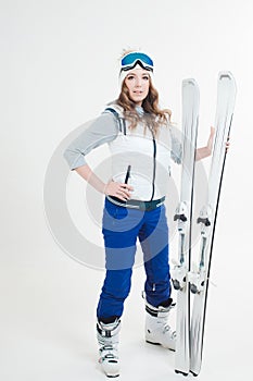 Smiling girl skier in a hat and mask for skiing. A young woman in clothes for skiing and outdoor activities.