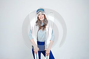 Smiling girl skier in a hat and mask for skiing. A young woman in clothes for skiing and outdoor activities.