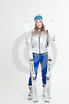 Smiling girl skier in a hat and mask for skiing. A young woman in clothes for skiing and outdoor activities.