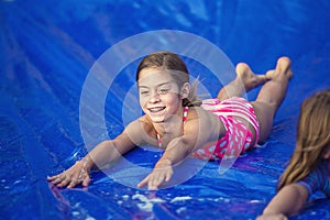 Smiling girl sliding down an outdoor slip and slide photo