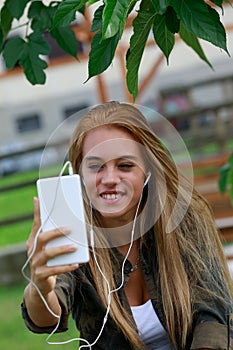 Smiling girl with smarphone oudtoors in the park