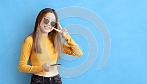 Smiling girl with smartphone in hand shows victory sign