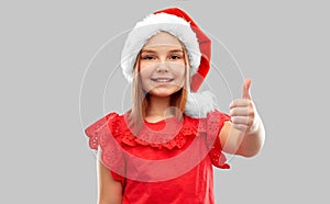 Smiling girl in snata helper hat showing thumbs up