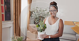 Smiling girl is standing in middle of living room in new rented purchased apartment decorating house after moving