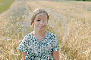 A smiling girl standing in the middle of a rural field