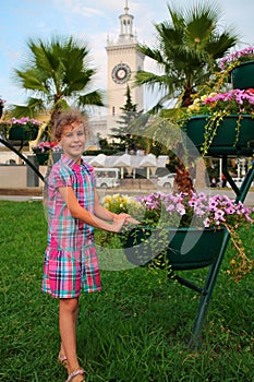 Smiling girl standing near flowerpot with flowers photo