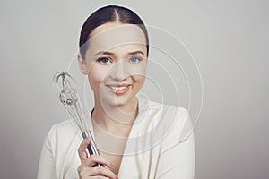 Smiling girl standing on whiter background stainless holding balloon whisk. Happiness and Cheerful young chef Concept. Beautty