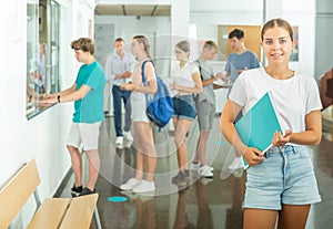 Smiling girl student standing with papers on college campus