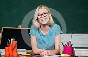 Smiling girl student or woman teacher portrait on green wall blackboard background. Portrait of college student in