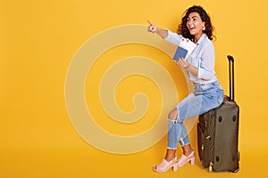 Smiling girl in stylish clothing isolated over pink background. Passenger traveling abroad, has air flight journey, holding