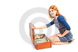 Smiling girl and suitcase full of money