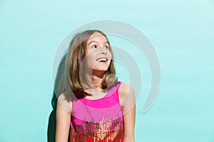Smiling girl on turquoise background looking up
