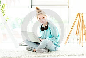 Smiling girl using laptop in light room