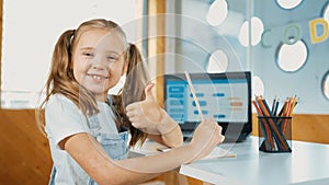 Smiling girl using laptop while look and show thumb up to camera. Erudition.