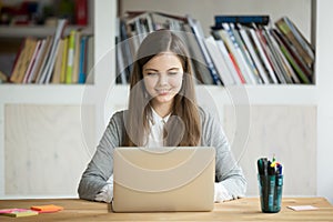 Smiling girl using laptop, student studying at home, digital edu