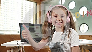 Smiling girl using laptop and turn around to show thumb up to camera. Erudition.