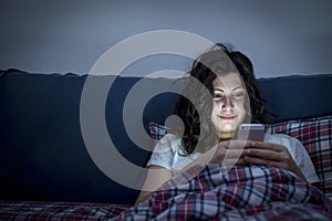 Smiling girl using smartphone in bed