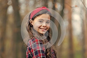 Smiling girl wear knotted headband. Biggest Hair Accessory Trends. Adorable little girl checkered shirt wear red