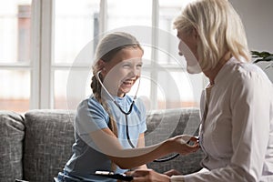 Smiling girl wear stethoscope play with doctor at home