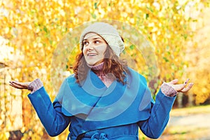 Smiling girl wearing autumn coat, knitted hat outdoors. Woman walking at autumn park. Autumn fashion, lifestyle. Happy girl