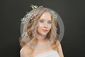 Smiling girl with white flowers in blonde hair on black background