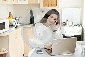 The smiling girl working on laptop at home