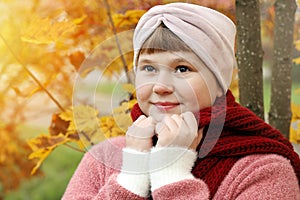 Smiling girl wrap oneself in red scarf to warm in autumn