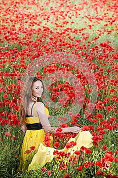 Smiling girl with yellow scarf in poppy field