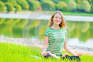 Smiling girl-yogi performs exercises in a green park