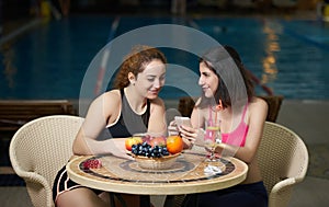 Smiling girlfriends eating breakfast with fruits and juice