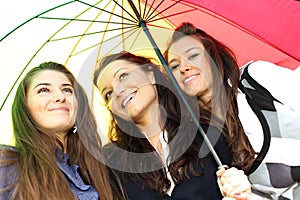 Smiling girlfriends under umbrella