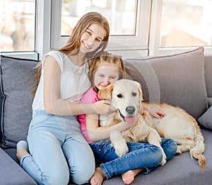 Smiling girls cuddling lovely dog