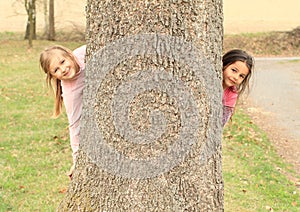 Smiling girls hiding behind tree