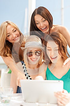 Smiling girls looking at tablet pc in cafe