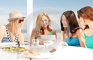 Smiling girls looking at tablet pc in cafe