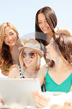 Smiling girls looking at tablet pc in cafe