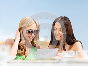 Smiling girls looking at tablet pc in cafe