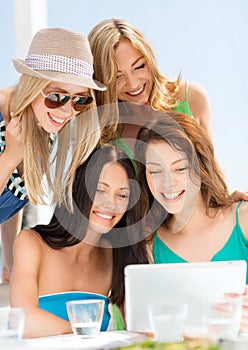 Smiling girls looking at tablet pc in cafe