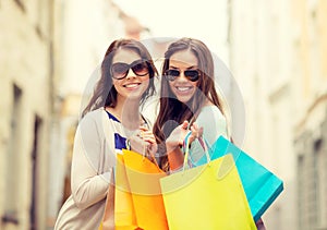 Smiling girls in sunglasses with shopping bags