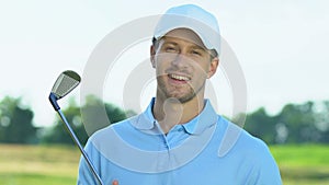 Smiling golf player holding iron club posing to camera, hobby, leisure activity