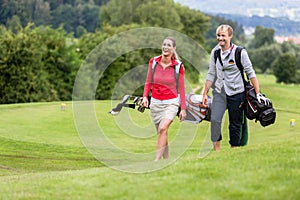 Smiling golf players carrying their club bags
